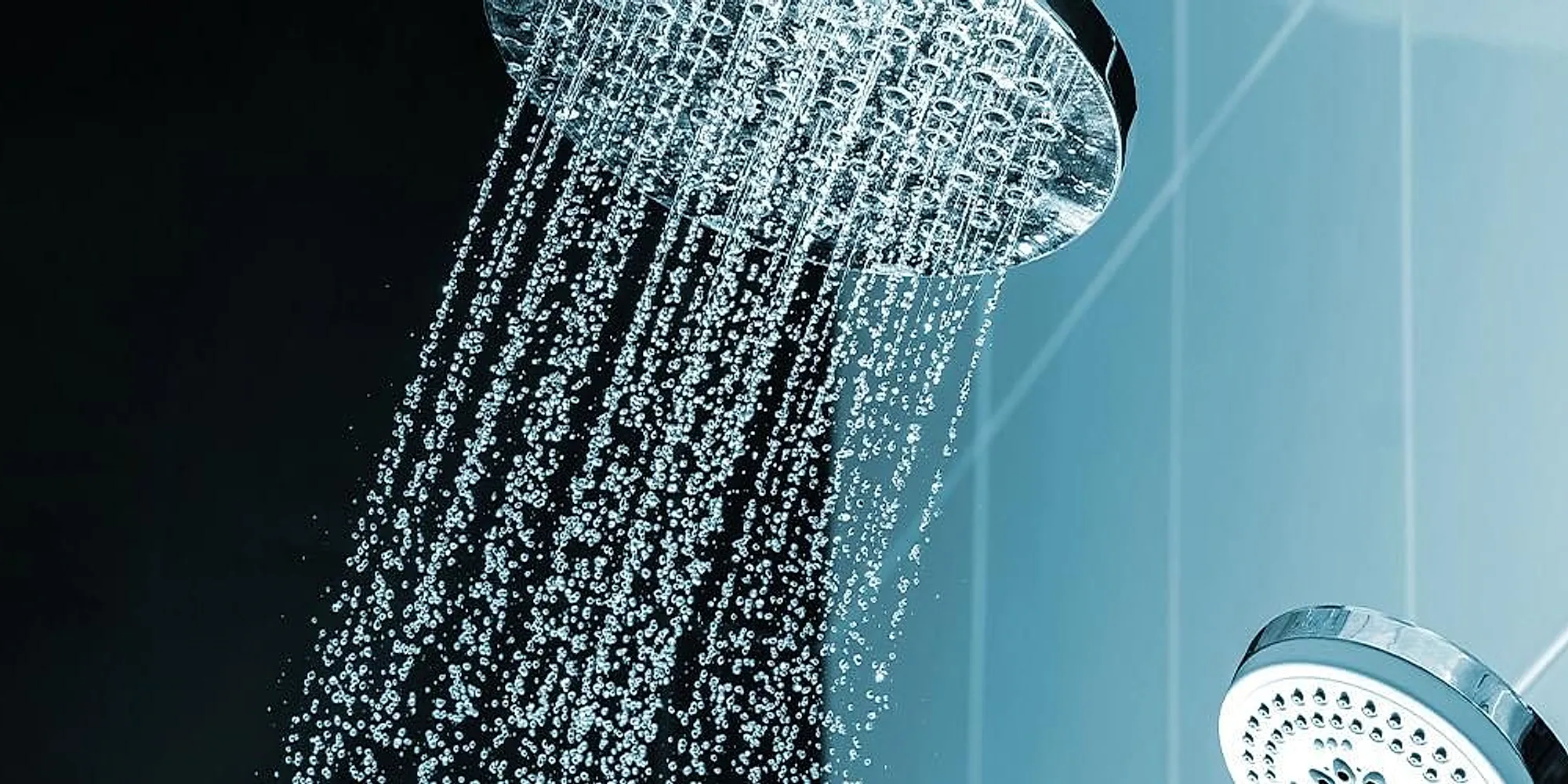 A shower head running against a dark tiled wall