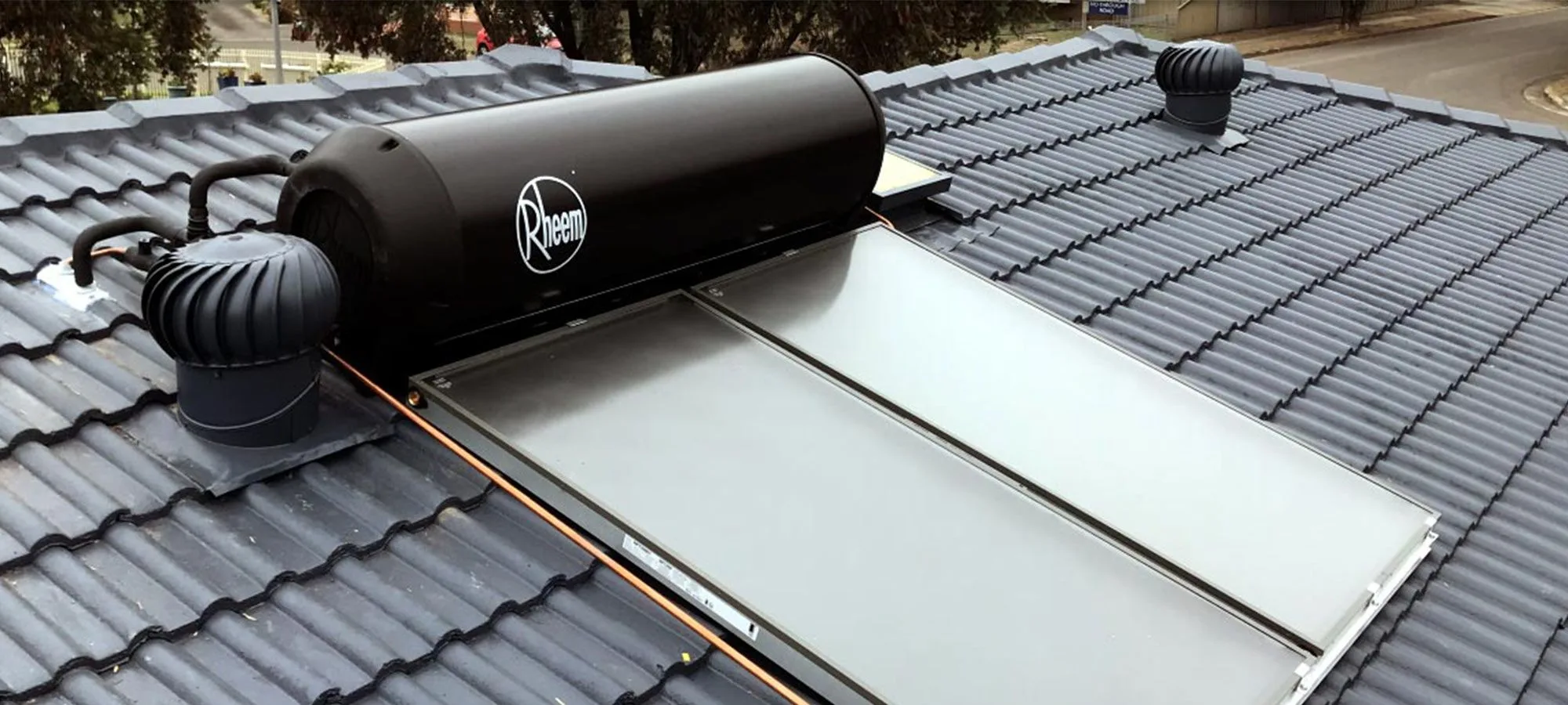 A Rheem solar hot water system installed on a tiled roof, with copper flow and return pipework