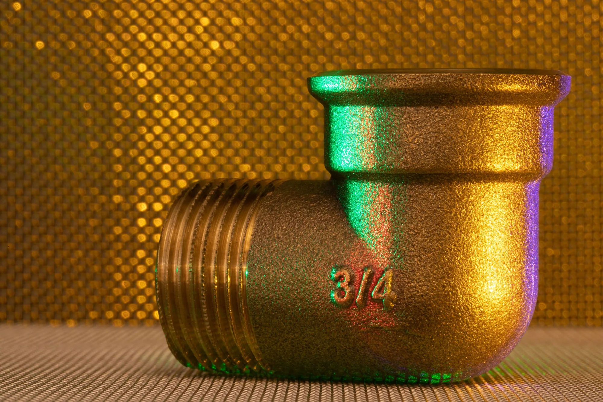 A brass three-quarter inch pipe fitting on a gold ground