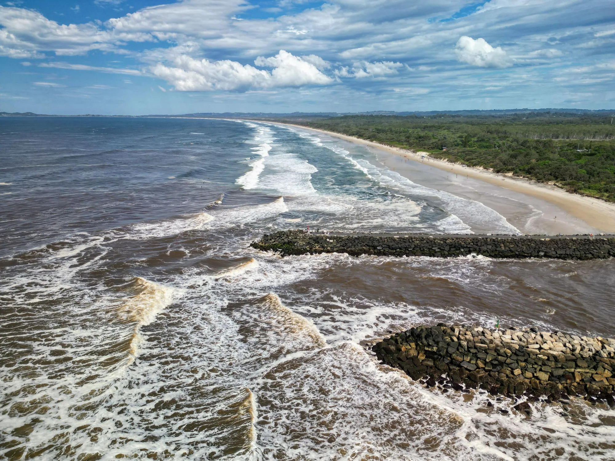 Aerial view of surf breaking along a sandy shoreline