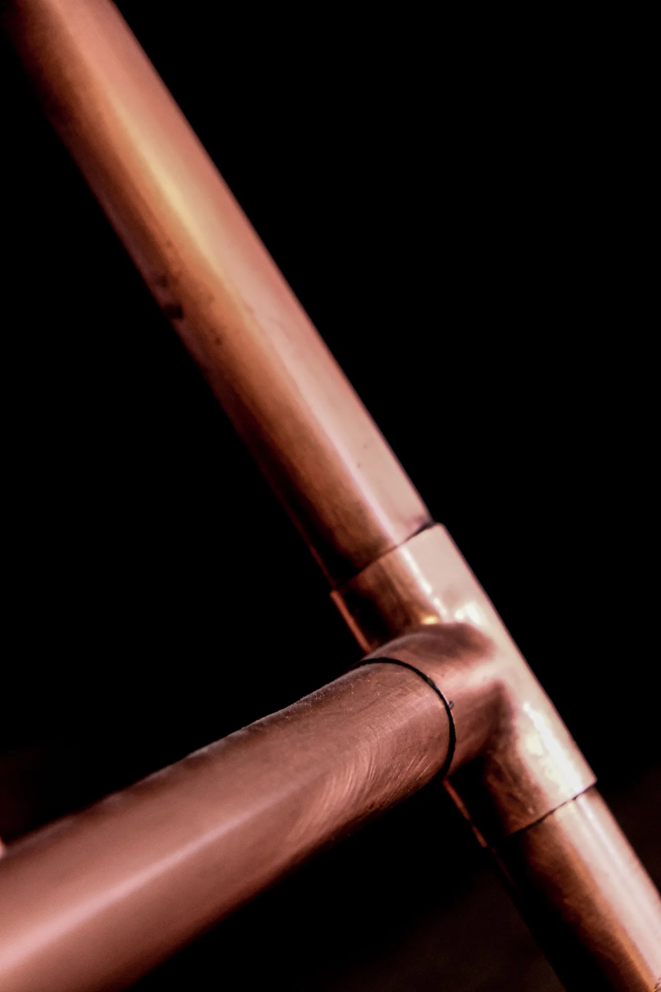 A copper pipe and fitting against a black background