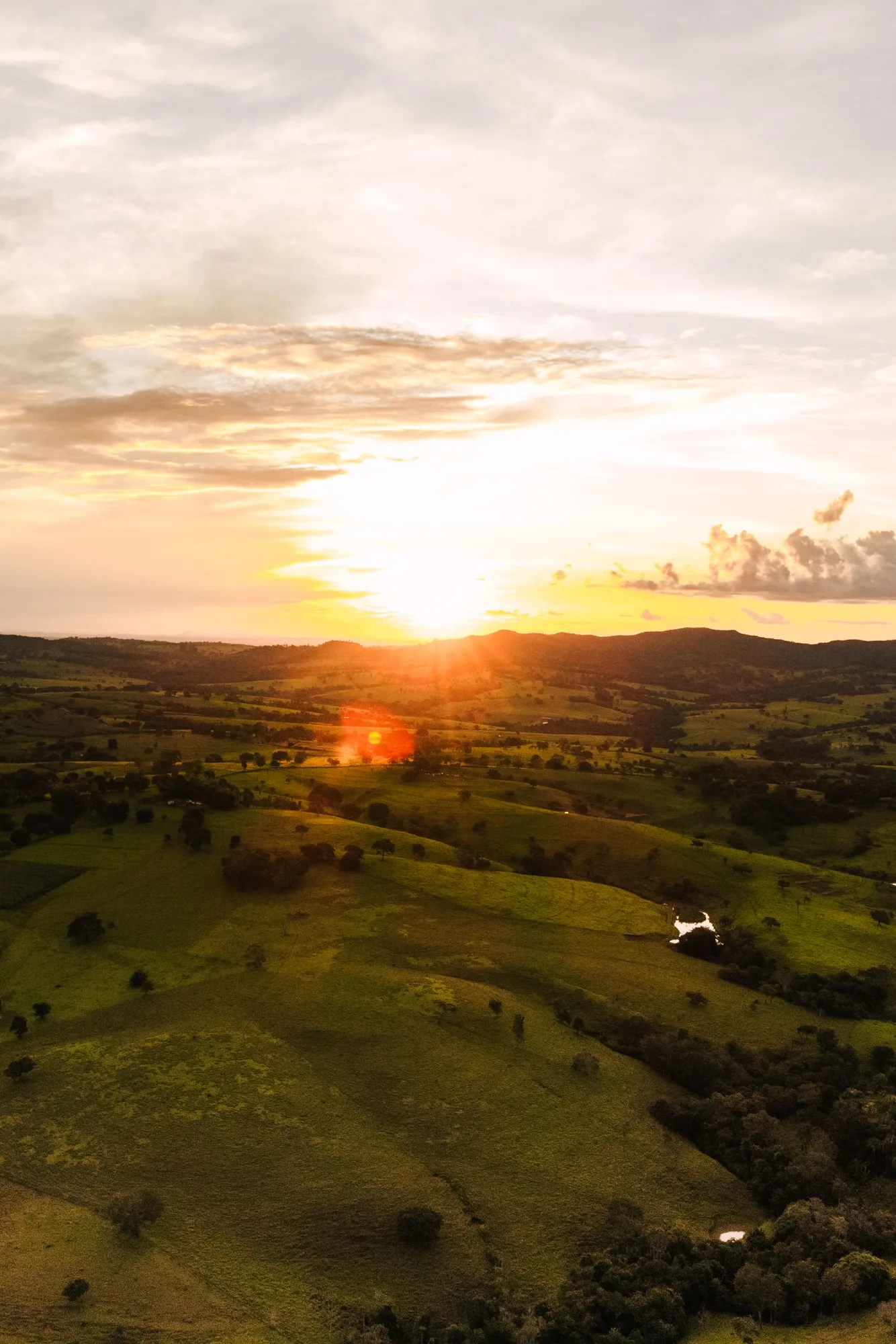 Aerial view of a golden sunset over rolling green hills