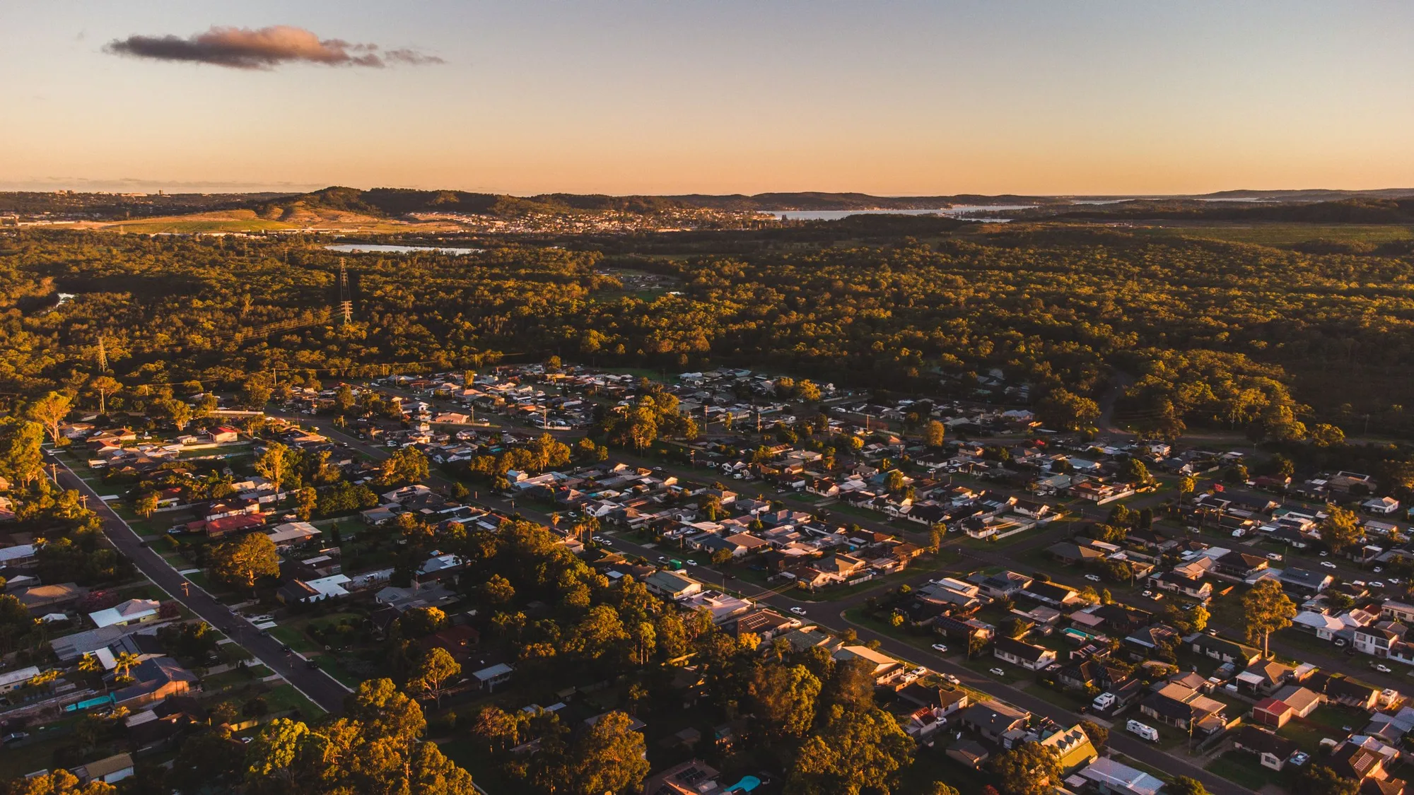 Aerial view of a residential area and forest at sunset